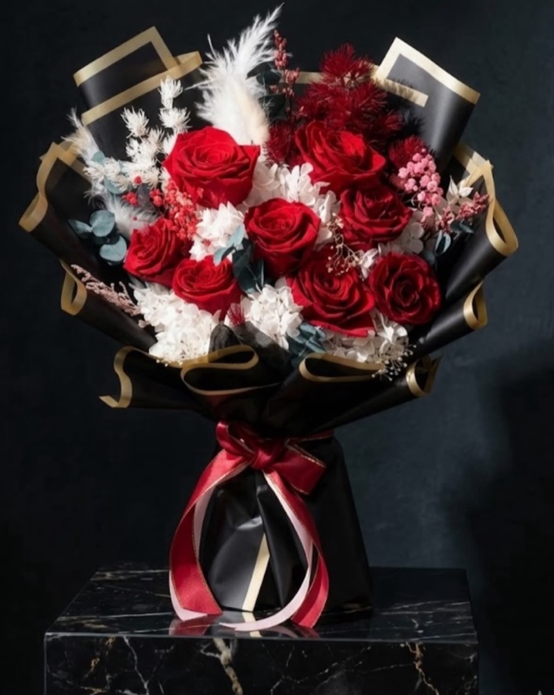 紅玫瑰配白色及酒紅配花,黑金邊包裝與紅色蝴蝶結花束